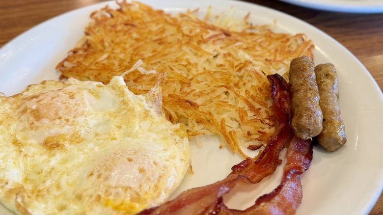 A breakfast plate of eggs, hash browns, bacon, and sausages