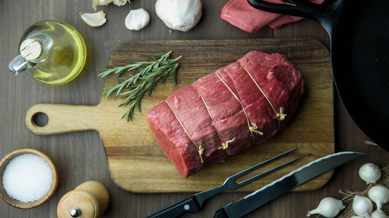 Raw eye of round beef cut ready for roasting with butcher twine on cutting board