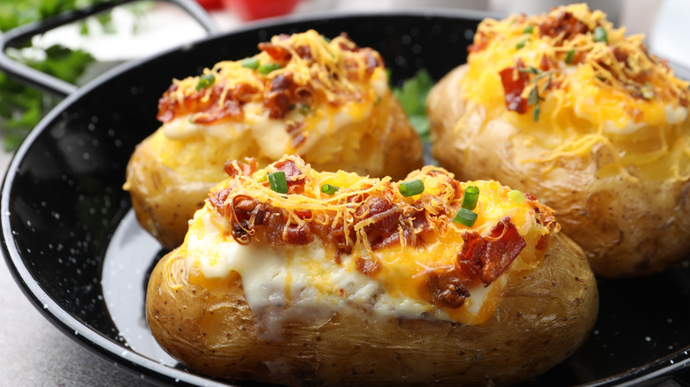 Tasty stuffed baked potatoes in baking dish on grey table