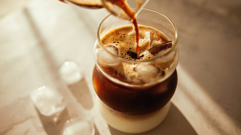 Iced coffee poured into a glass with cream on the bottom