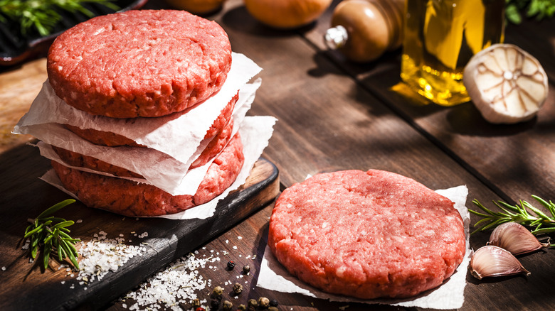 raw burgers on wooden surface