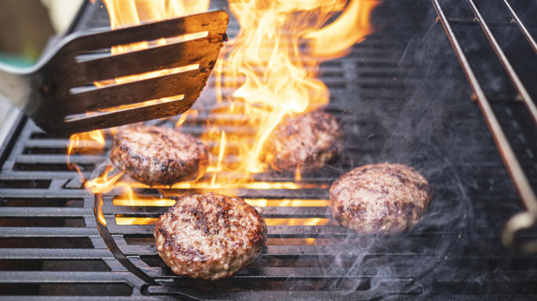 burgers cooking on a fiery grill