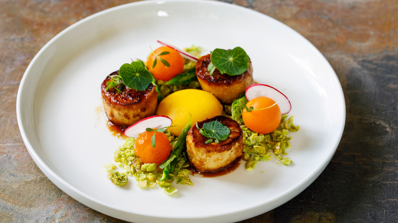 Confit yolk on plate with scallops, vegetables