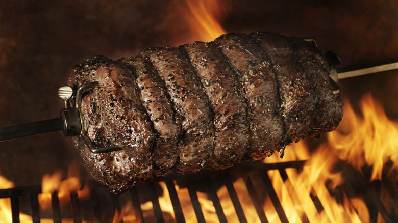 Beef on a rotisserie spit over a fiery grill