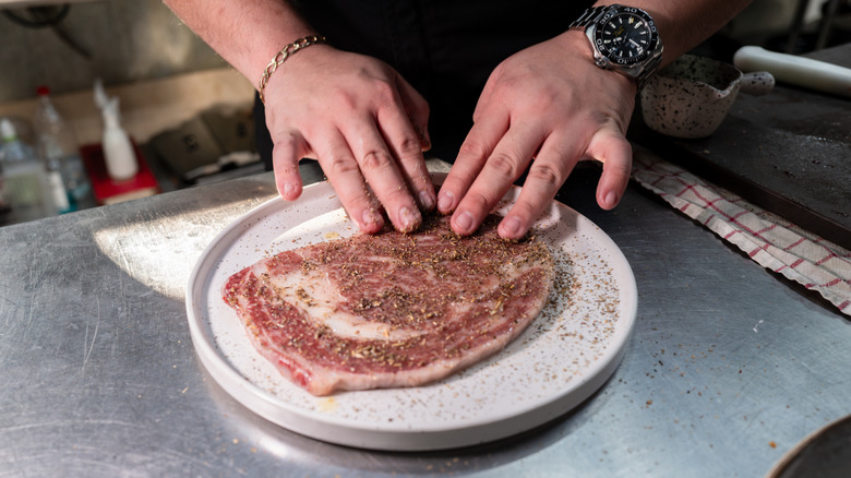 Person dry rubbing a steak