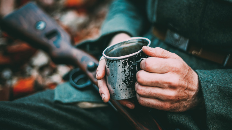 soldier drinking coffee with rifle on lap