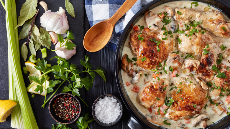 Pan of braised chicken in creamy gravy next to ingredients and spoon