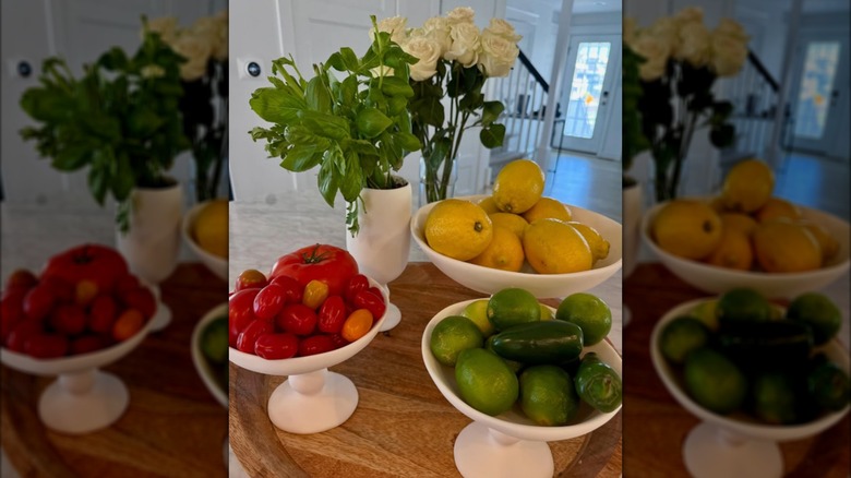 Three pedestal bowls with fruits and vegetables sitting on a wooden table