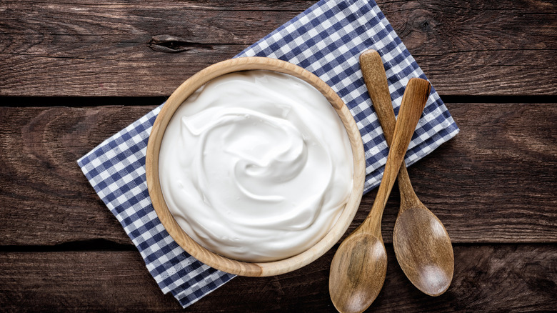 Sour cream in a wooden bowl on a blue-and-white checkered napkin