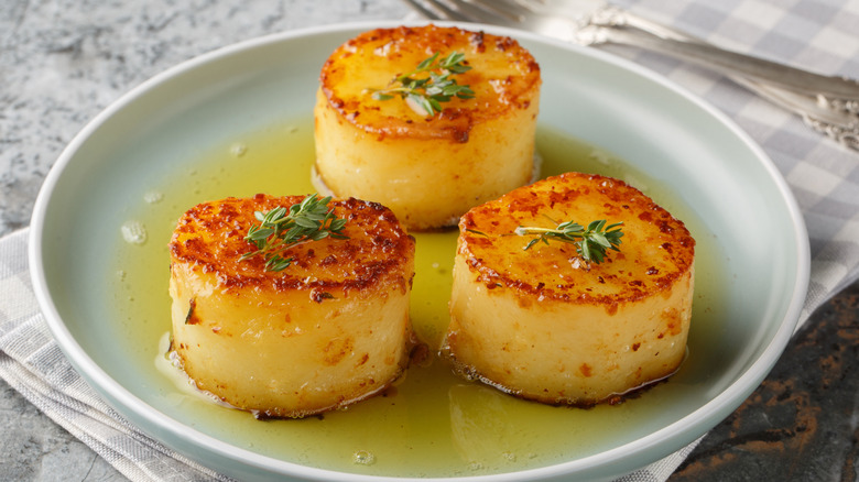 fondant potatoes on a plate with herbs