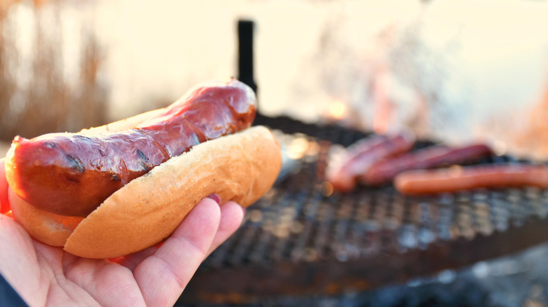 Hot dog in hand with more on the grill