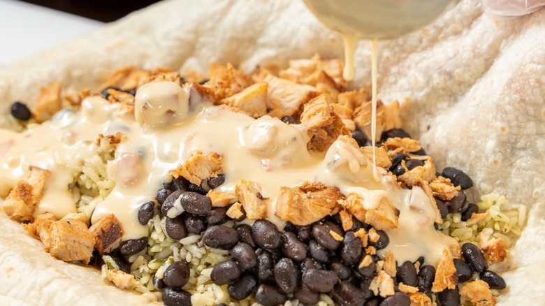 An employee preparing a burrito from Pancheros Mexican Grill