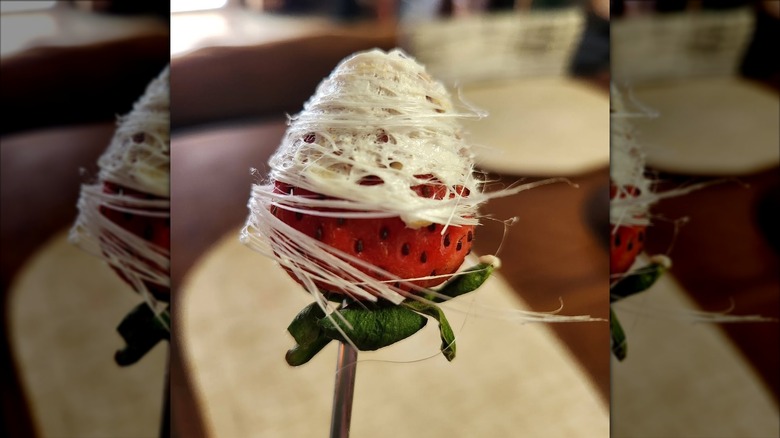 Skewered strawberry upside down, wrapped in melted marshmallow