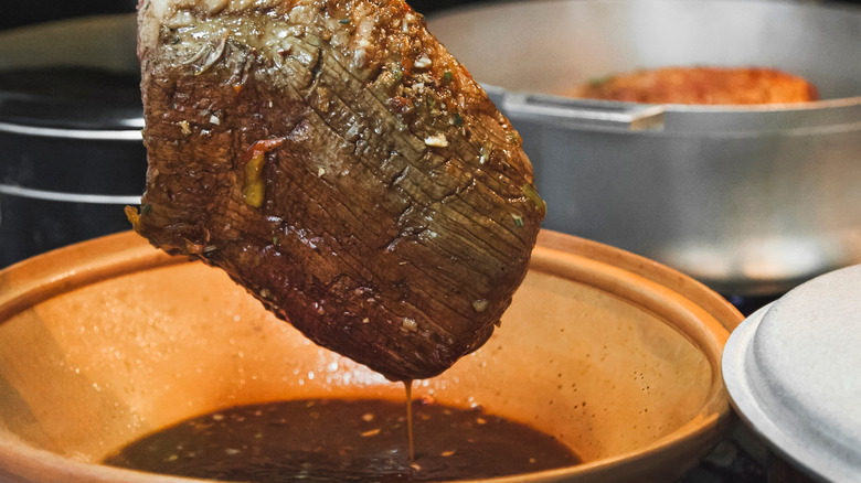 brisket being dipped in its own gravy