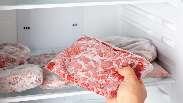 hand taking out frozen meat from freezer