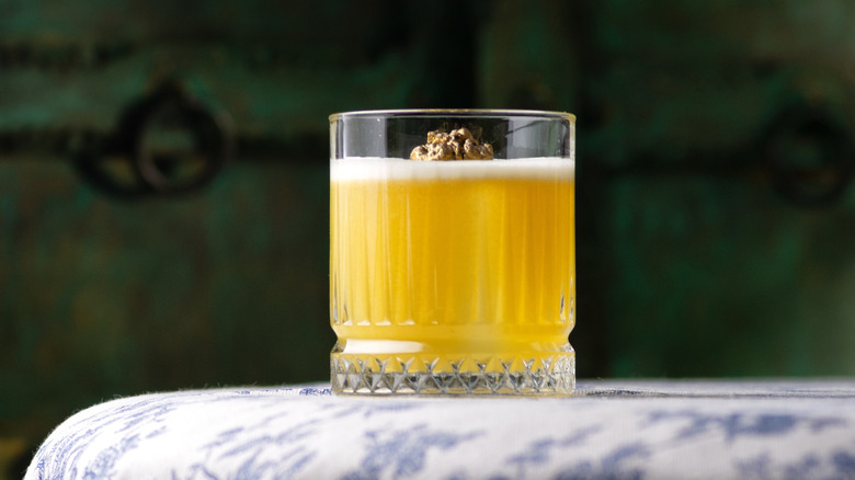 A Penicillin Scotch cocktail in a tumbler on a blue and white tablecloth with a dark green background