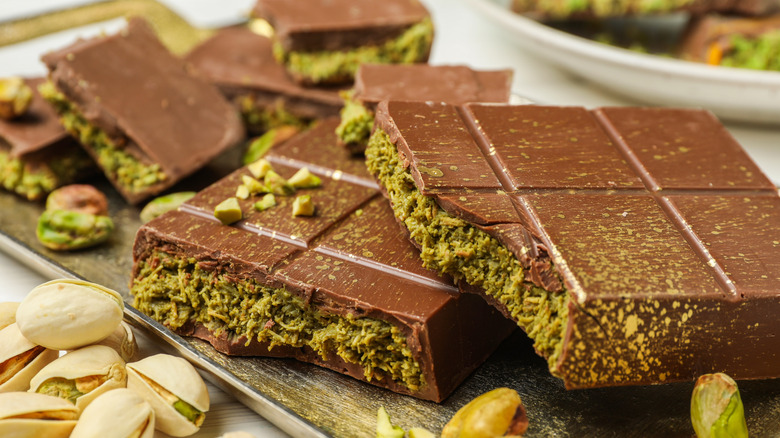pieces of Dubai chocolate on a tray with pistachios in shell