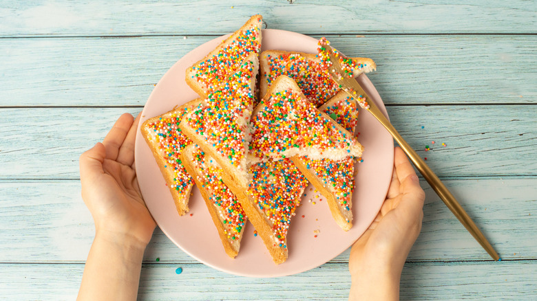 Sliced fairy bread on a plate with a gold knife
