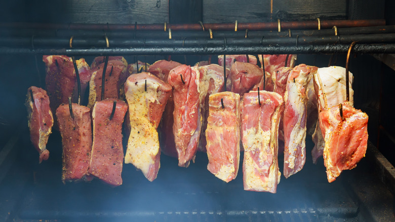 Various cuts of meat hanging in an old-fashioned cold smoker