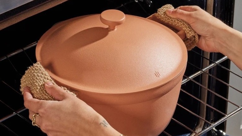 Hands taking the Our Place Perfect Pot in Spice out of an oven