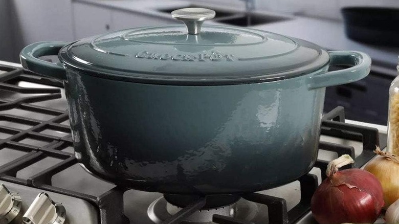 A blue Crock Pot Artisan Oval Enameled Cast Iron Dutch Oven on a stovetop