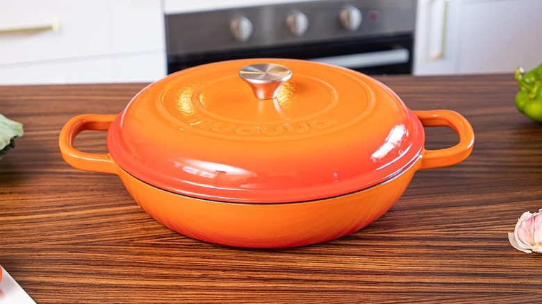 A fiery orange Nuovva Shallow Cast Iron Casserole on a kitchen counter