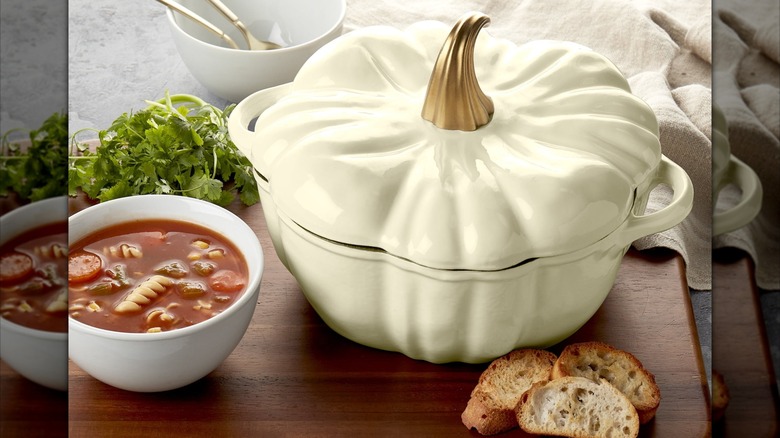 A cream-colored Smith & Clark Pumpkin Enameled Cast Iron Dutch Oven next to a bowl of soup and bread