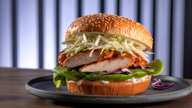 A chicken burger has cabbage on it.