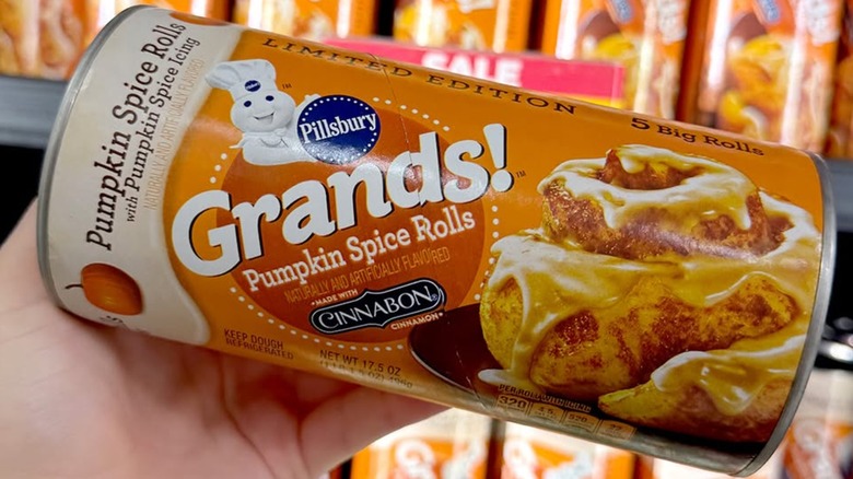 Hand holding Pillsbury Grands! Pumpkin Spice Roll container