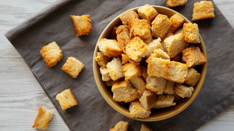 A bowl of croutons on a gray cloth.