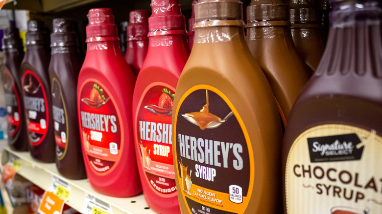 A shelf displaying a variety of Hershey's syrups at a grocery store