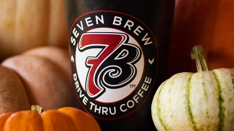 A 7 Brew hot coffee cup surrounded by colorful pumpkins