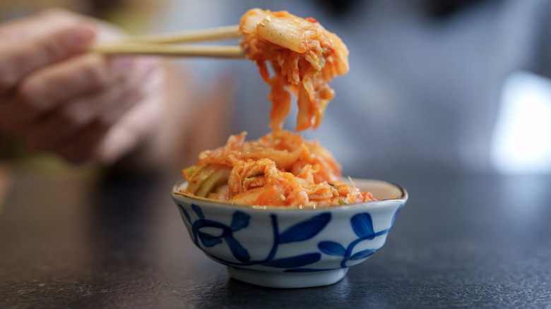 Close-up of a foodie holding kimchi with chopsticks