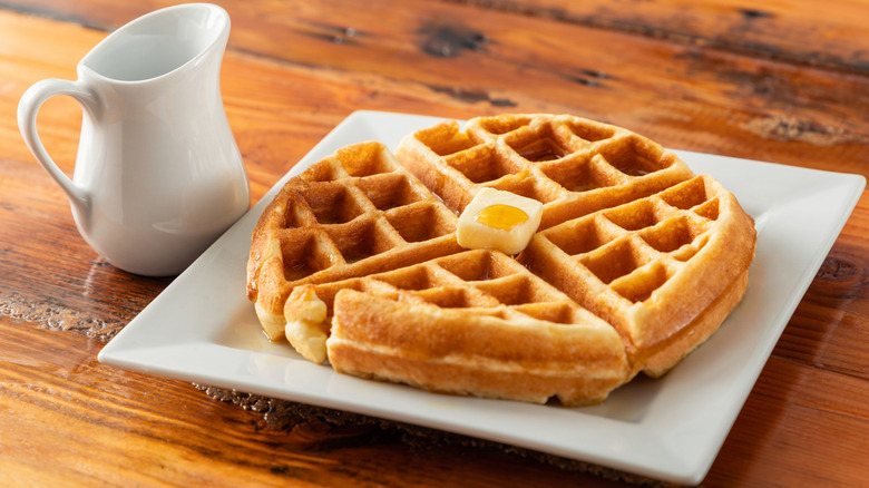 Waffle on a plate with butter and syrup.