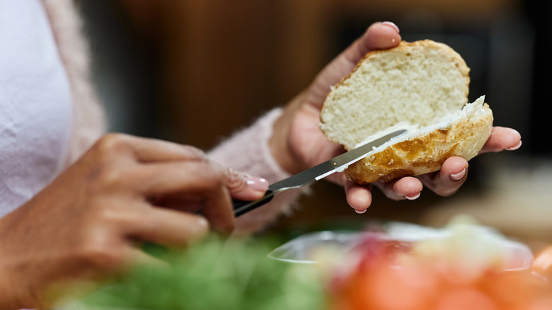 person spreading sauce on bread with a knife