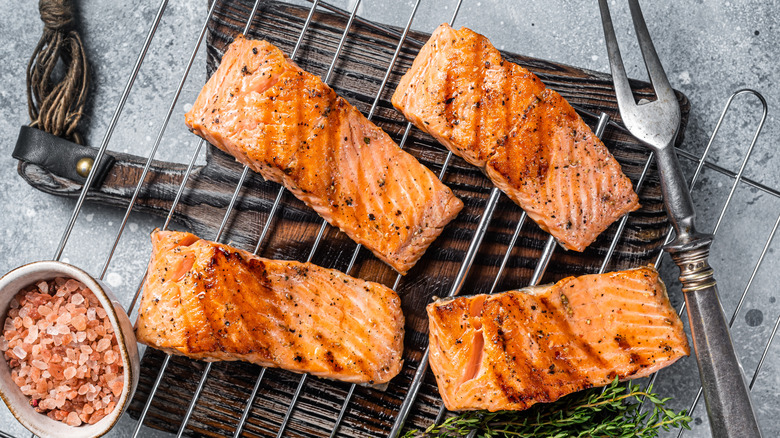 Four grilled salmon steaks, with cooking tools and seasonings