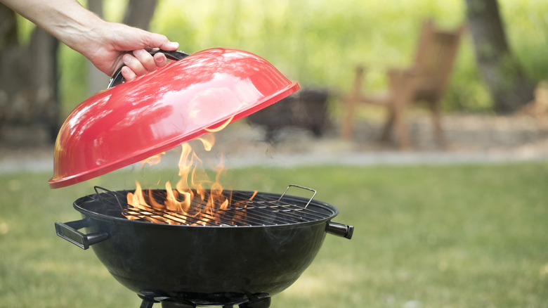 Person opening a grill with a red top