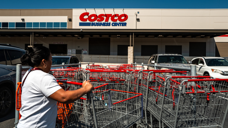 A woman returns a shopping cart in the parking lot of a Costco Business Center