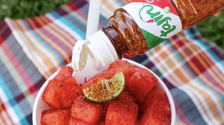 Tajín bottle being sprinkled on watermelon
