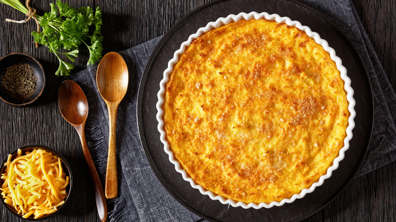 Cheesy scalloped corn casserole in a white baking dish