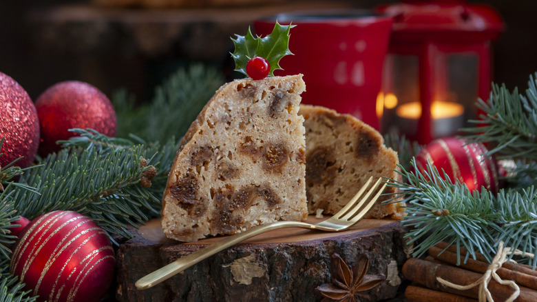 Sliced Christmas pudding with a fork, pine branches, and ornaments