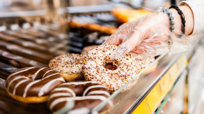 person getting a donut out of a display case