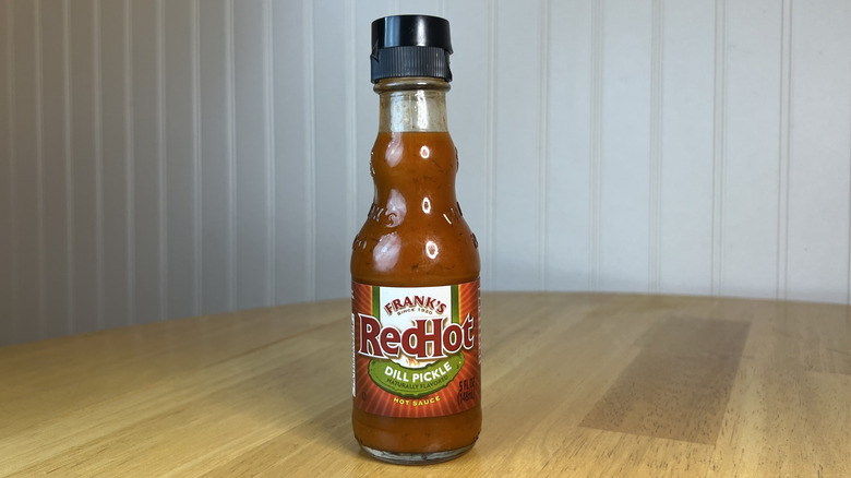 Bottle of Frank's RedHot Dill Pickle Hot Sauce on wooden table