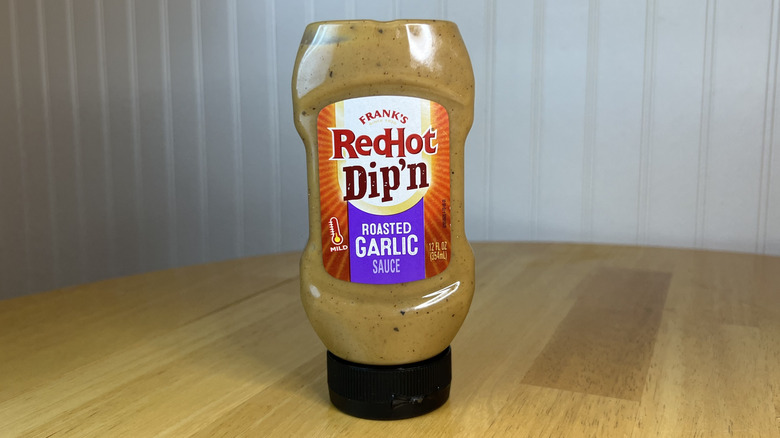 Bottle of Frank's RedHot Dip'n Roasted Garlic Sauce on wooden table