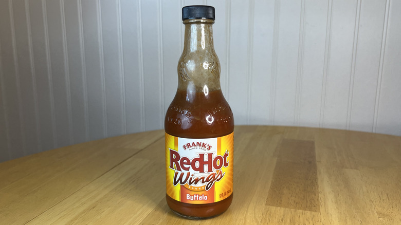 Bottle of Frank's RedHot Wings Buffalo Sauce on wooden table