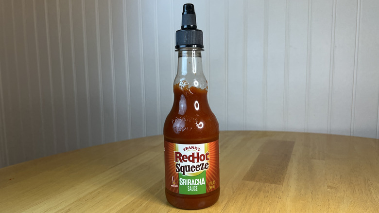Bottle of Frank's RedHot sriracha sauce on wooden table