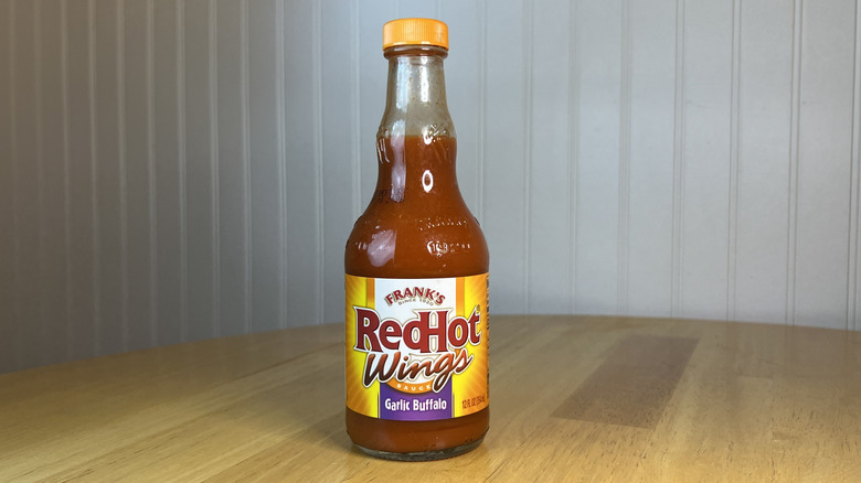 Bottle of Frank's RedHot Wings Garlic Buffalo Sauce on wooden table