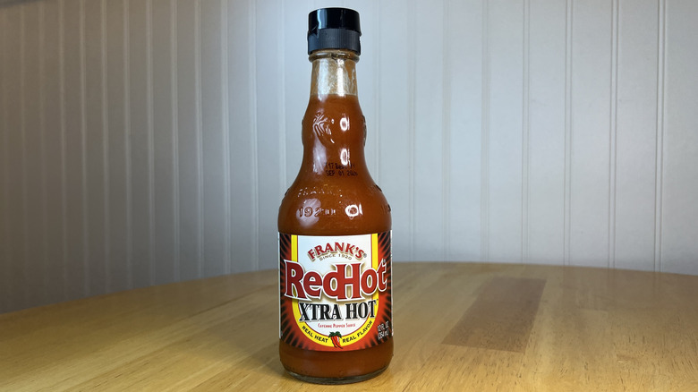 Bottle of Frank's RedHot Xtra Hot sauce on wooden table