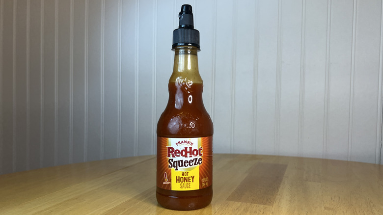 Bottle of Frank's RedHot Squeeze hot honey sauce on wooden tabl