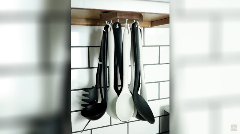 Spoons hanging from rack under cabinet